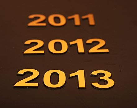  Upcoming years 2011, 2012 and 2013 as golden digits over dark background