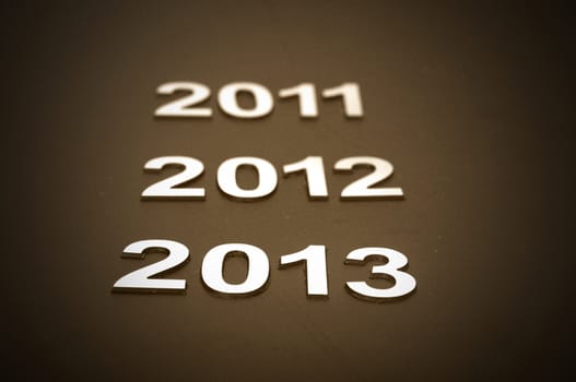 Upcoming years 2011, 2012 and 2013 as chrome digits over black background