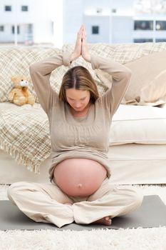 Pregnant woman doing yoga on the floor of her living-room at home