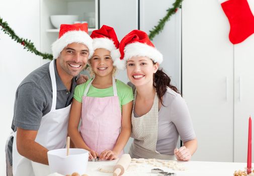 Portrait of a man with wife and daughter cooking Christmas biscuits in the kitchen