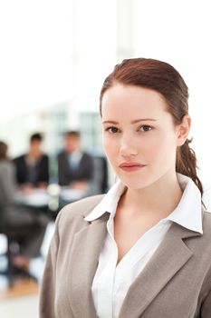 Serious businesswoman standing during a meeting with her team at the office