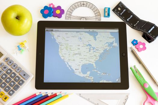 Ipad 3 with maps and school accesories on white background