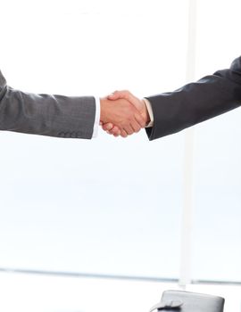 Close up of two businessmen shaking their hands standing in the office at work