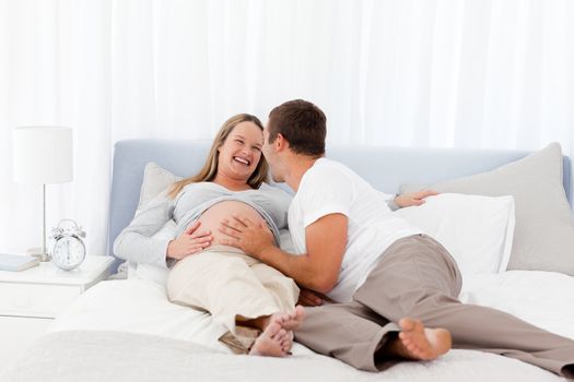 Smiling future parents liyng on the bed 