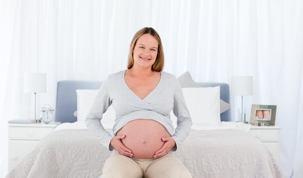 Joyfull pregnant woman in her bedroom smiling at the camera