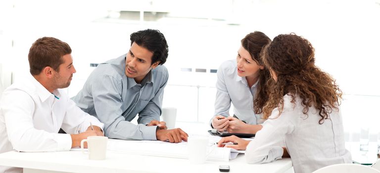 Four engineers discussing about a new project around a table 