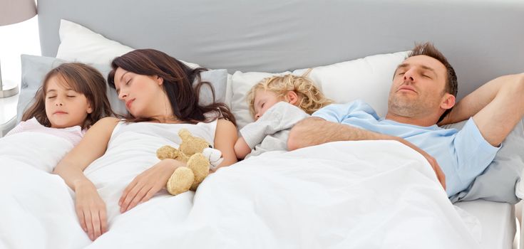 Cute family sleeping together in the parents's bed