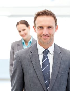 Two smiling business people posing in a row at work