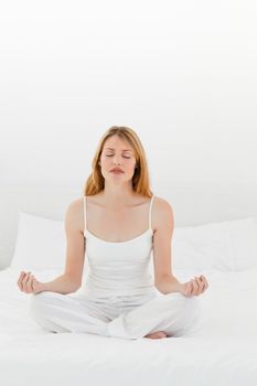 Woman practicing yoga on her bed at home