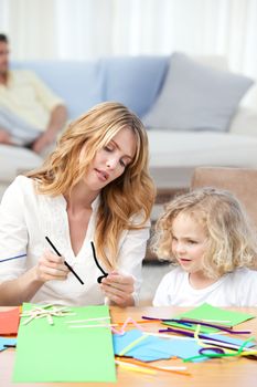 Woman and  her daughter cutting paper at home
