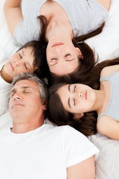 Family lying down on their bed at home