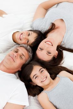 Family lying down on their bed at home