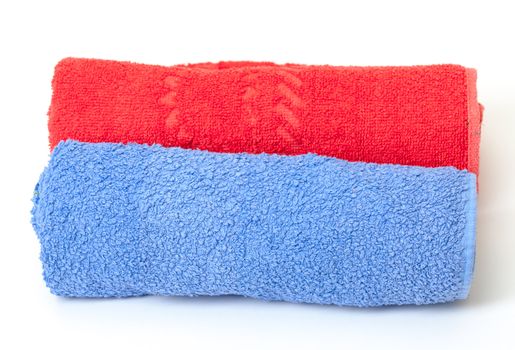Two thick absorbent rolled red and blue bath towels on white background conceptual of health, hygiene and a spa treatment