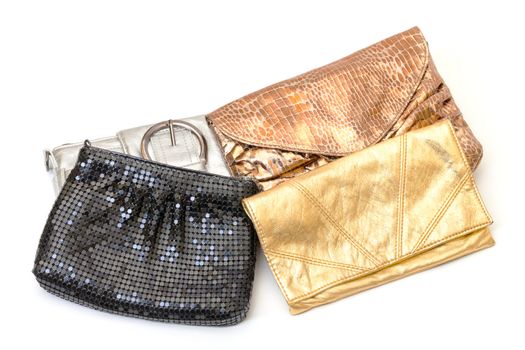 Selection of four leather evening bags in black, silver and two shades of gold with different designs and styles on a white background