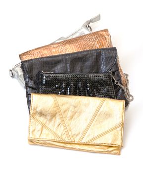 Selection of four leather evening bags in black, silver and two shades of gold with different designs and styles on a white background