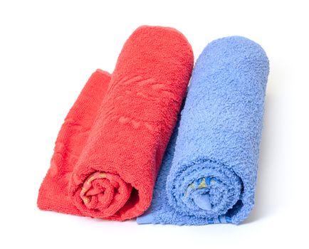 Two thick absorbent rolled red and blue bath towels on white background conceptual of health, hygiene and a spa treatment