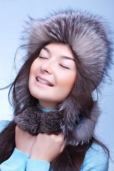 happy woman in fur cap on the blue background