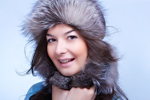smiling winter woman in fur cap on blue background