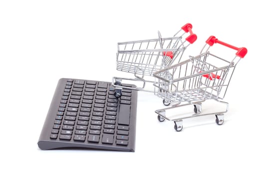 Computer keyboard with two miniature wire shopping carts conceptual of online retail sales and purchases isolated on white