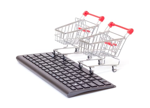 Computer keyboard with two miniature wire shopping carts conceptual of online retail sales and purchases isolated on white