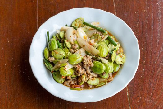 Stir-fried of Spicy Pork with Stink Beans on wooden background.