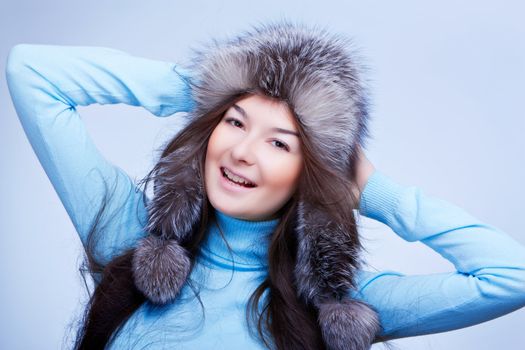joyful woman in fur cap on blue background