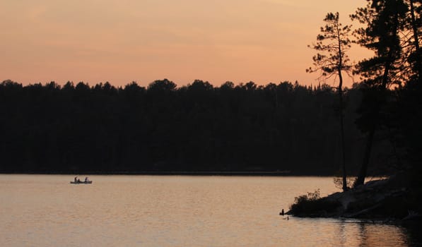 The silhouette of canoers in Algonquin Provincial Park at  dusk.