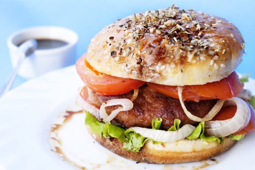 Burger with meat and baked vegetables on a blue background