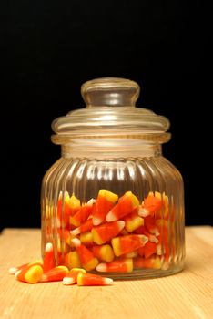 A glass candy jar full of the holloween treat candy corn.