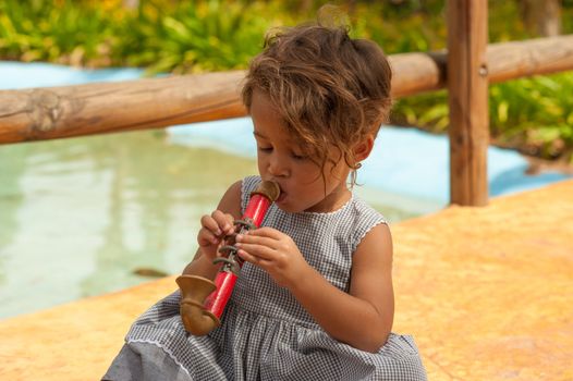 Cute Hispanic girl playing with a toy saxophone