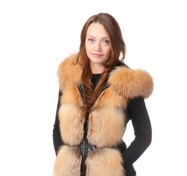 Stylish relaxed young woman in winter fur jacket standing with her hands in her pocket isolated on white