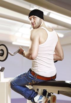 man makes exercises with bar in exercise room