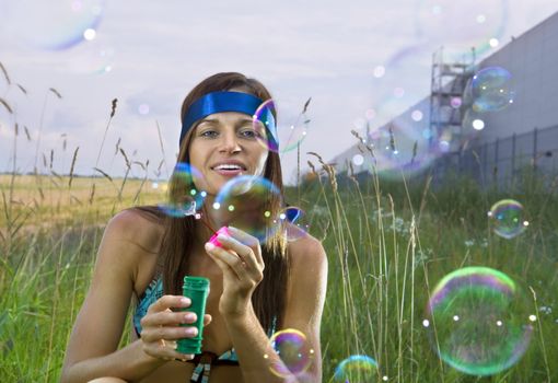 beauty young woman blowing soap bubbles in summer day