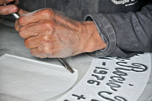 A tombstone engraver working on a tombstone.