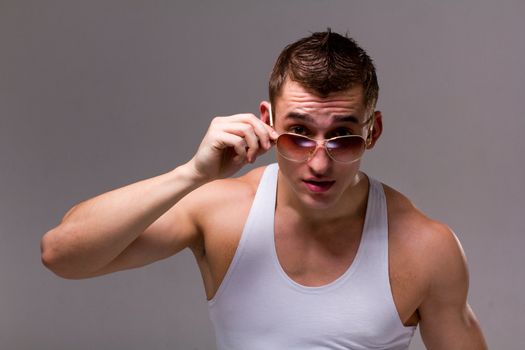 surprised man wearing black sunglasses posing on a gray background