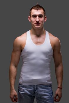 Young muscular man posing on a gray background
