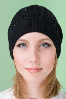 young woman wearing a winter cap on a green background
