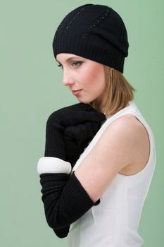 knitwear. young woman wearing a winter cap and gloves on a green background