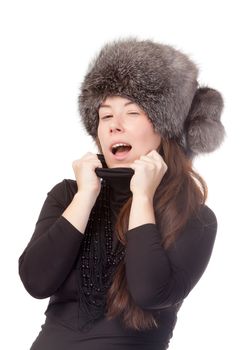 Vivacious woman in a winter outfit with a fur hat on white background