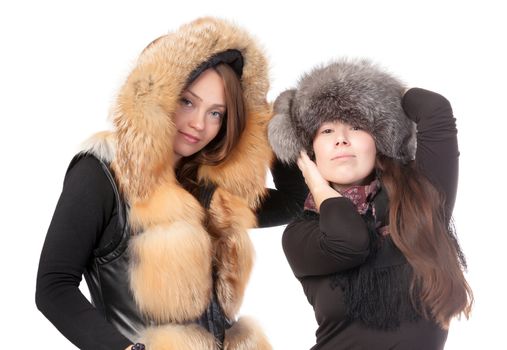 Two attractive women dressed for winter posing together on a white background in fur trimmed garments