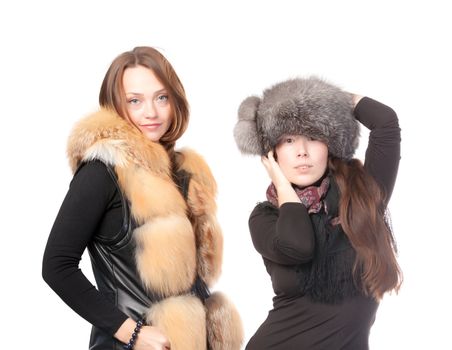 Two attractive women dressed for winter posing together on a white background in fur trimmed garments