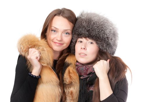 Two attractive women dressed for winter posing together on a white background in fur trimmed garments