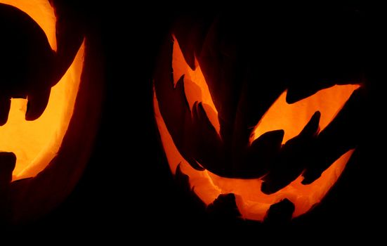 A closeup shot of two carved pumpkins on Halloween night.