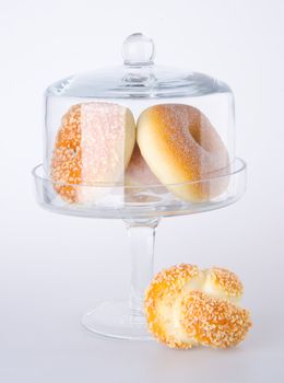 Donut, bun, cookie & glass jar on the background