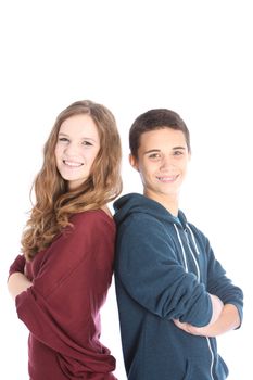 Happy teenage boy and girl standing back to back with their arms folded smiling at the camera isolated on white