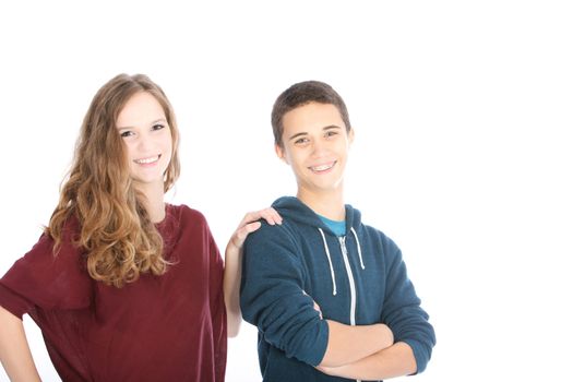 Affectionate attractive teenage boy and girl standing side by side with tjhe girls hand on his shoulder smiling at the camera on white