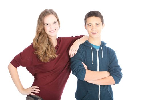 Young smiling attractive teenage brother and sister standing side by side with the girl leaning affectionately on the boys shoulder isolated on white