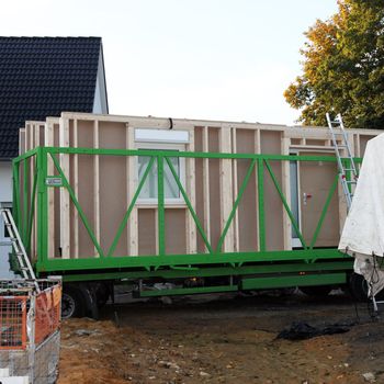 Walls of a new build prefabricated timber house standing in a trailer on the builing site waiting to be offloaded