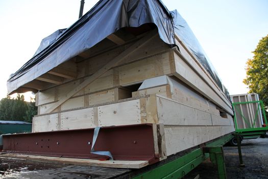 Sections of a prefabricated wooden home loaded on a trailer at the building site waiting to be erected and installed