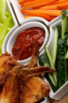 Chicken Wings and Snacks with Barbecue Sauce, Cucumber, Bell Pepper and Carrot Sticks closeup